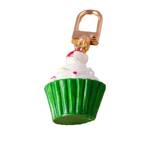 Süßer Cupcake Schlüsselanhänger mit weißer Creme und bunten Punkten auf grünem Sockel
