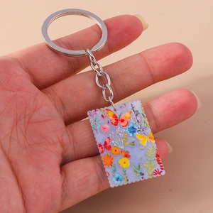 Close-up of square butterfly keychain with vibrant floral pattern and wavy edges