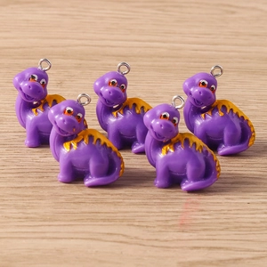 Close-up of five cute purple resin dinosaur charms with yellow spikes for DIY crafts