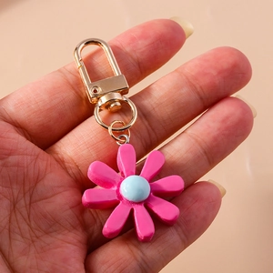 Detailansicht eines rosa Schlüsselanhängers aus Harz in Gänseblümchenform mit Goldkarabiner