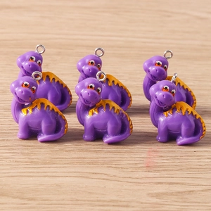 Close-up of purple resin dinosaur charms with yellow spikes and metal hanging rings