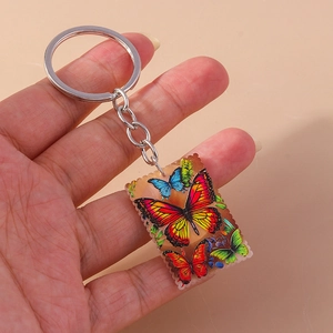 Detail of colorful butterfly keychain with wavy edges held by hand in a warm light