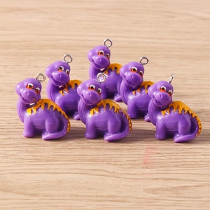 Detailed view of six purple cartoon dinosaur charms with orange accents and metal hooks