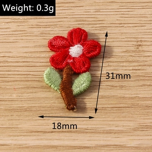Macro view of 31x18mm flower embroidery patch with detailed red and green stitching