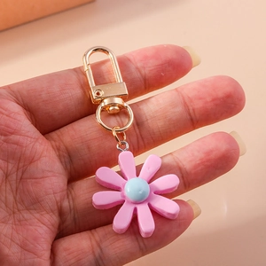 Nahaufnahme eines Schlüsselanhängers aus rosa Harz-Gänseblümchen mit Goldverschluss