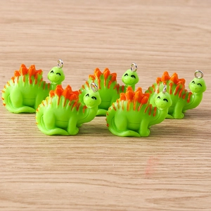 Detailed close-up of five cute green cartoon resin dinosaur pendants with metal loops