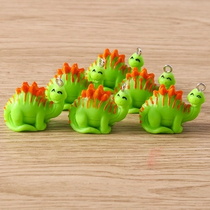 Close-up of cute green dinosaur charms with orange plates and silver hooks for DIY jewelry