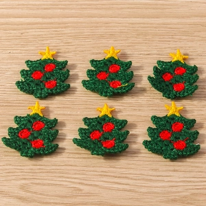 Detailed embroidery texture of deep green Christmas tree patches with stars and red dots