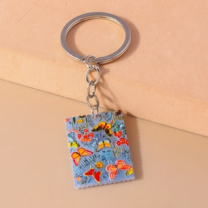 Detailed close-up of a square butterfly art keychain with stamp edge and silver metal ring