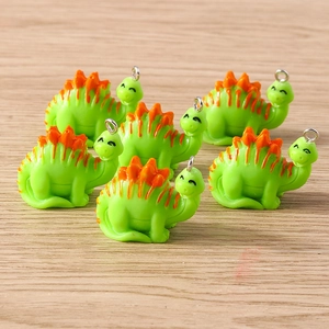 Close-up of six resin green dinosaur charms with orange spikes and silver metal rings