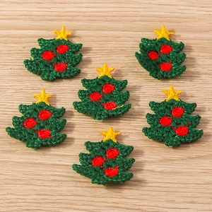 Detail view of six green embroidered Christmas tree patches on a wooden background