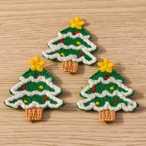 Three embroidered Christmas tree patches with stars on rustic wooden background
