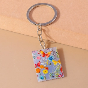 Close-up of a rectangular acrylic keychain with butterfly patterns and stamp-style edges