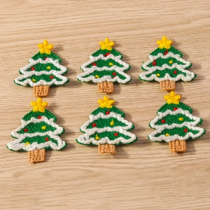 Detailed embroidery texture of Christmas tree patches laid on a light wood background