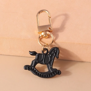 Détail d'un porte-clés cheval à bascule noir avec reliefs et fermoir mousqueton doré