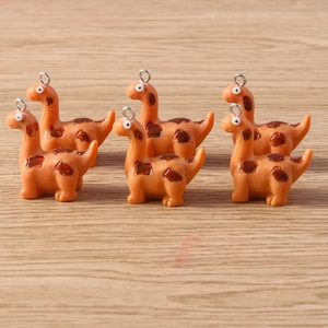 Detail of cute orange resin dinosaur charms with silver eyelet pins for DIY jewelry making