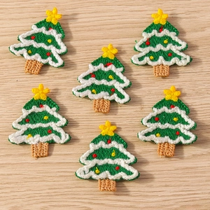 Close-up of 6 embroidered Christmas tree patches with neat green stitching on wood surface