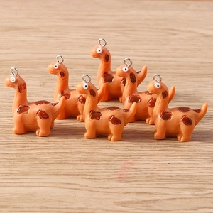 Close-up of cute orange resin dinosaur charms with silver eye hooks for DIY jewelry