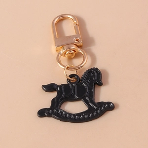 Détail d'un porte-clés cheval à bascule noir avec mousqueton doré et anneau brillant