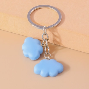Detail of blue cloud keychain with resin pendants and silver metal ring on warm base