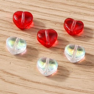 Macro shot of colorful transparent heart-shaped beads for DIY jewelry on light wood surface