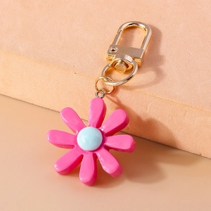 Detail eines rosa Harzblumen-Schlüsselanhängers mit blauem Kern und Goldkarabiner