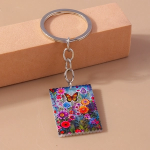 Detail of square butterfly keychain with colorful floral patterns on a display stand
