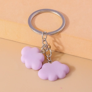 Detail of purple cloud pendants on a silver metal keyring against orange background