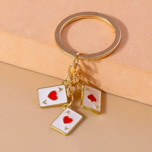 Makroansicht goldener Schlüsselanhänger mit Emaille-Herz und Karo-Poker-Anhängern