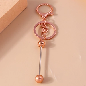 Macro shot of rose gold geometric keychain hardware with barbell pendant on beige background
