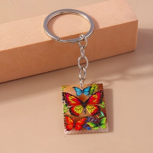 Detail of a rectangular butterfly keychain with wavy edges and colorful artistic prints