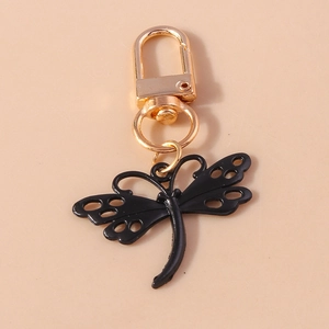 Détail du porte-clés libellule avec ailes noires ajourées et fermoir mousqueton doré