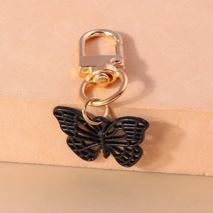 Détail d'un porte-clés papillon ajouré noir avec un fermoir mousqueton doré élégant
