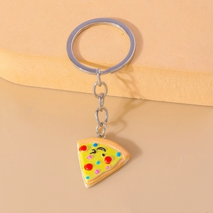 Cute cartoon pizza slice keychain with winking face emoji and colorful toppings on beige background