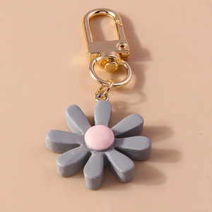 Detail eines grauen Gänseblümchen-Schlüsselanhängers mit rosa Mitte und Goldverschluss