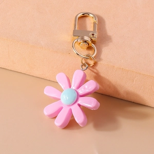Detail eines rosa-blauen Gänseblümchen-Anhängers aus Harz mit goldenem Karabiner
