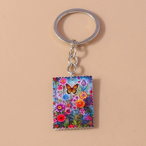 Detail of square keychain with colorful butterfly painting and scalloped stamp edges