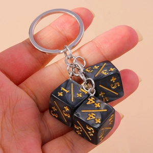 Macro shot of black marble resin dice keychain with gold engraved numbers and silver metal ring
