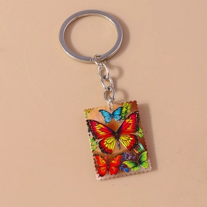 Macro detail of a postage stamp style keychain with colorful oil painting butterfly motifs