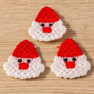 Macro detail of three handmade crochet Santa Claus charms on rustic wooden background