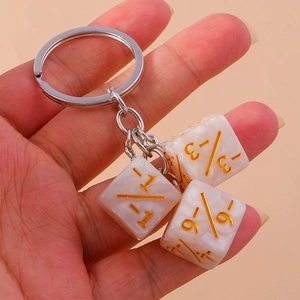 Detail of three white marble resin dice keychains with gold engraved numbers and metal ring