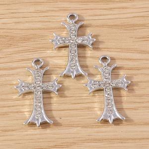 Three gothic silver alloy cross pendants with sparkling white zircons on wood surface