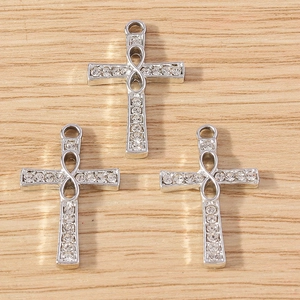 Three silver cross pendants with infinity symbol and rhinestones on wood surface
