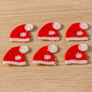 Detailed view of hand-knitted red and white Christmas hat pendants on a wooden background