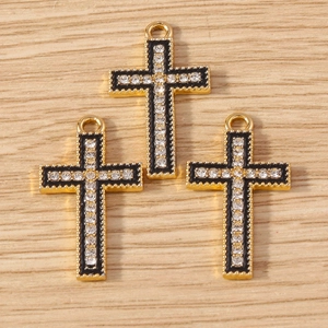 Macro shot of gold cross charms with black enamel inlay and sparkling white rhinestones