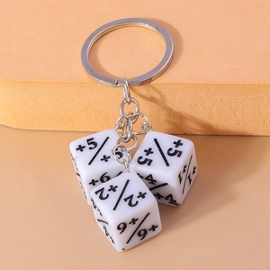 Close-up of three white dice keychains with black math symbols on a warm orange background