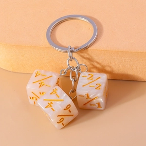 Macro shot of three marble textured dice pendants with gold numbers on a silver keychain