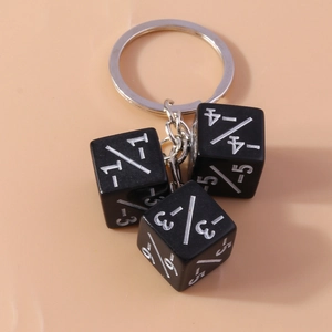 Close-up of black dice keychain with silver numbers on a light orange background