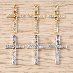 Macro detail of cross pendants with infinity symbol and zircons in gold and silver