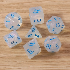 Detail of translucent white resin polyhedral dice set with blue numbers on wood background